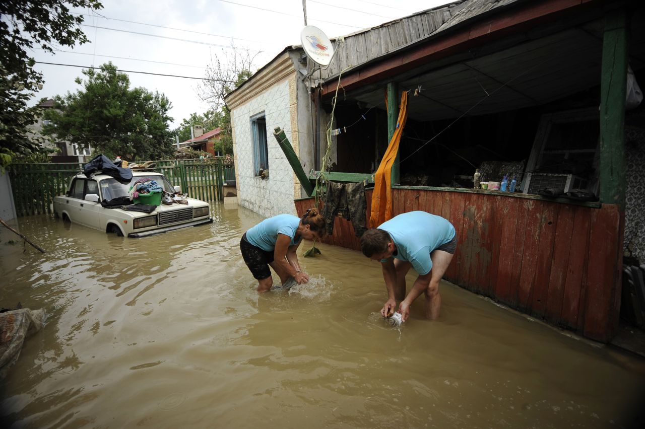 Locals work outside a home in Krymsk where floodwaters still stand Sunday.