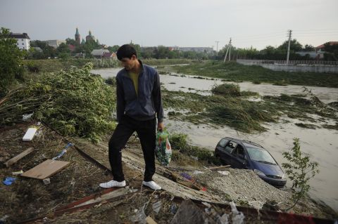 A man walks past an abandoned car Sunday in the town of Krymsk.
