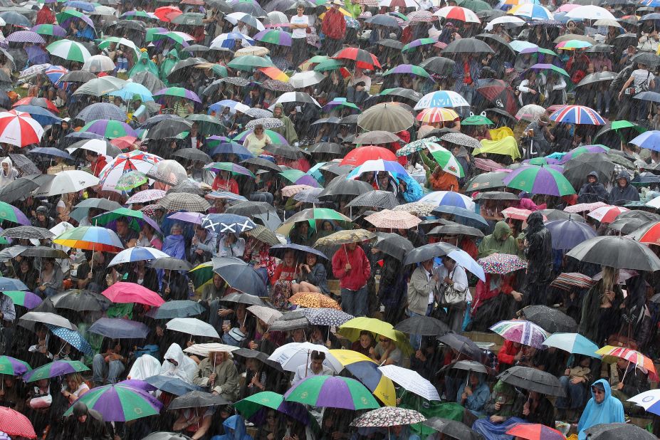Tennis fans shelter from a heavy downpour that developed during the match Sunday.