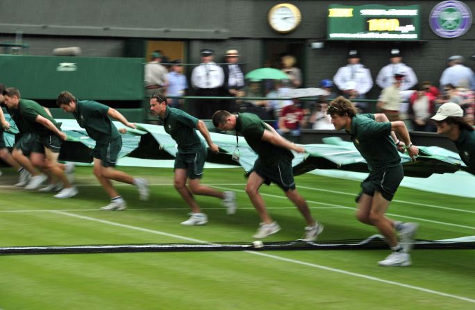 Ground staff pull a cover onto center court during a rain delay in the championship match. 