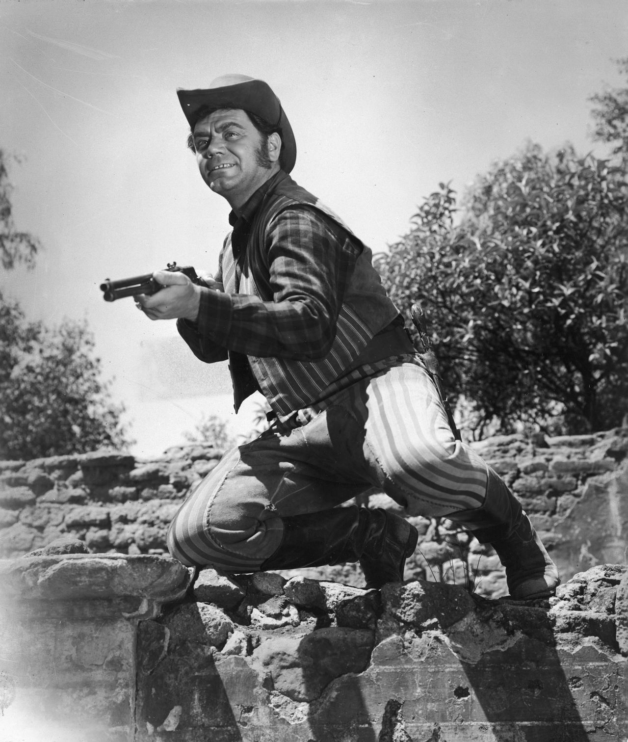 Ernest Borgnine steadies his rifle while acting in a Western film circa 1955.
