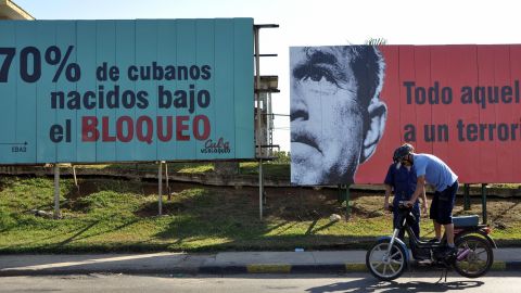 A Cuban checks his motorcycle in front of billboards alluding to the U.S. embargo on Cuba, on April 20, 2009 in Havana. 
