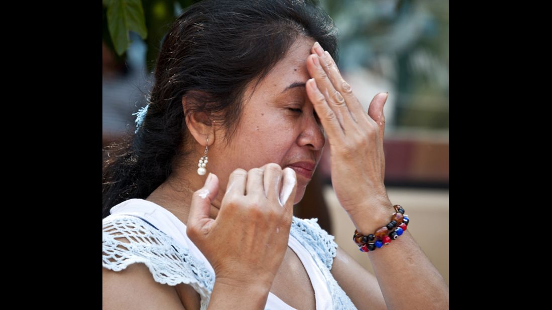 Fatima Domingpe applies sunscreen to her face near the Mosaic Fountain in downtown Silver Spring, Maryland, on Saturday, July 7. A record heat wave has been in the area for more than a week.