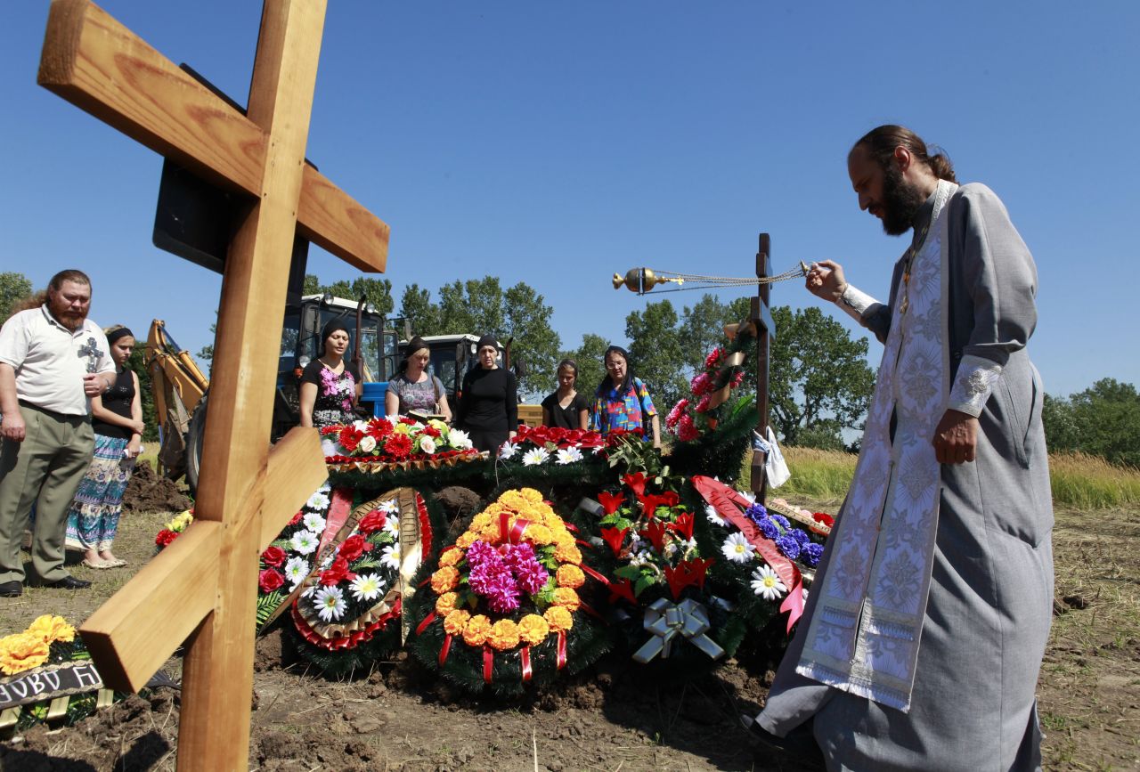 A priest conducts a funeral for Petr Ostapenko, 35, in Krymsk, Russia, on Monday, July 9. At least 171 people have been killed in flooding in the Krasnodar region since Friday.