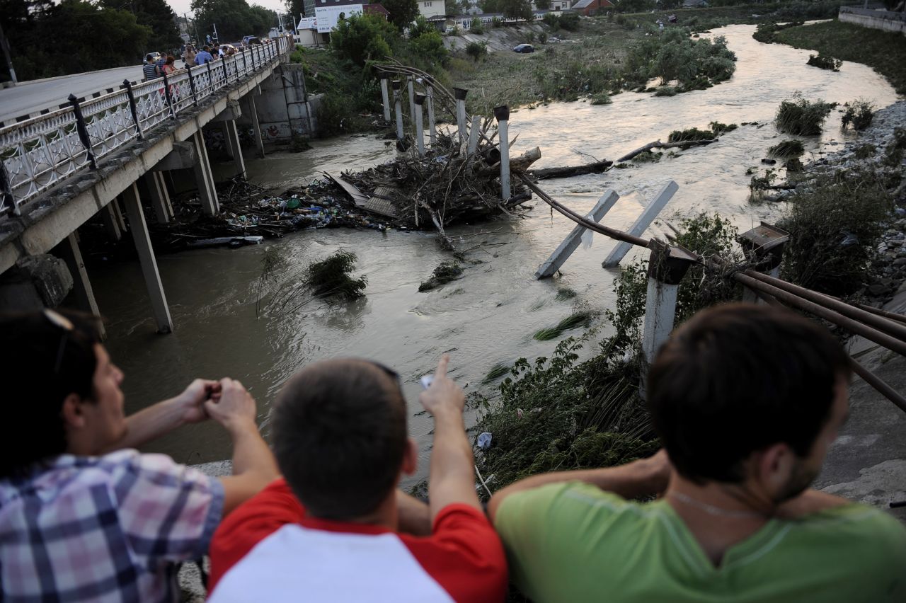 Residents look out over a river that contributed to the flooding in Krymsk on Sunday.