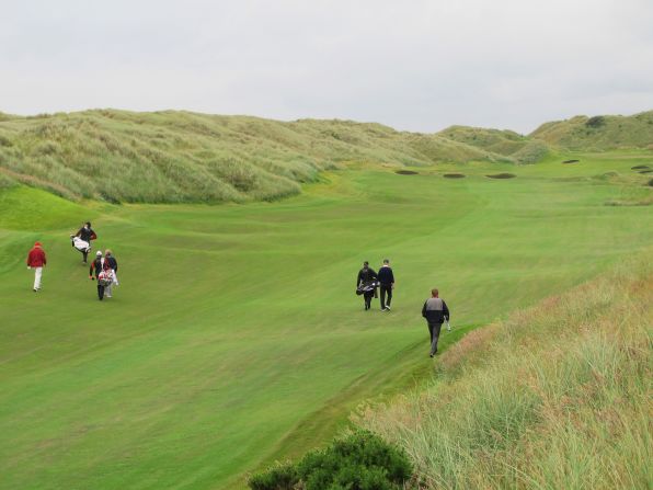 Trump, far left, marches down the fairway for the first time, accompanied by Montgomerie. The American's plans to continue construction have been unpopular with locals.