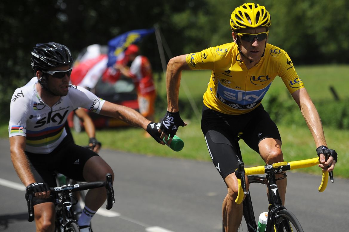 Overall race leader Bradley Wiggins, right, receives a water bottle handoff from Team Sky teammate Mark Cavendish on Wednesday.