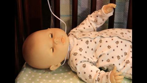 A doll is used to demonstrate how monitor cords pose a strangulation danger for babies. 