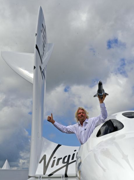 Richard Branson hangs out of the window of SpaceShipTwo, currently on display for the first time in Europe at the Farnborough Airshow, with a model of LauncherOne.  According to Branson, the maiden voyage for LauncherOne is expected to be 2015.