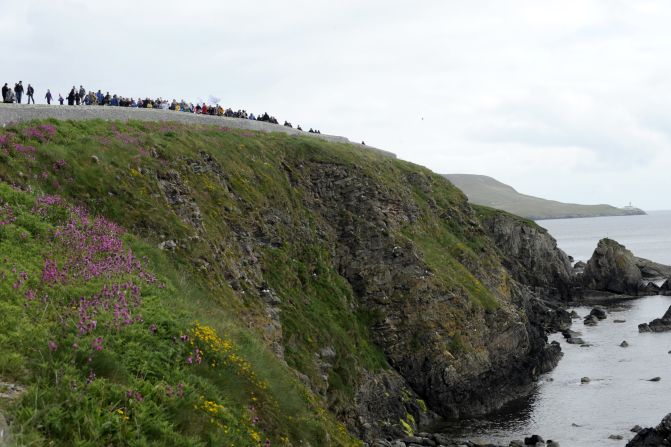 Andrea Strachan, a competitive swimmer, carries the Olympic flame along the shore in Lerwick, Scotland, on June 10.