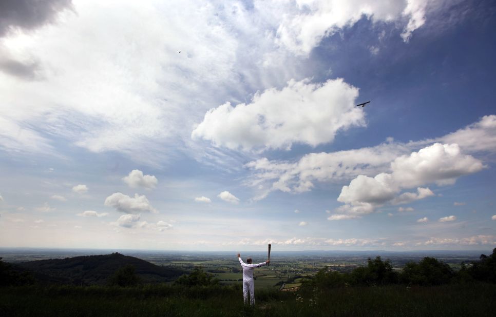 Torchbearer Eugene Perry carries the Olympic flame at Sutton Bank in the North Yorkshire Moors National Park in York, England, on June 20.