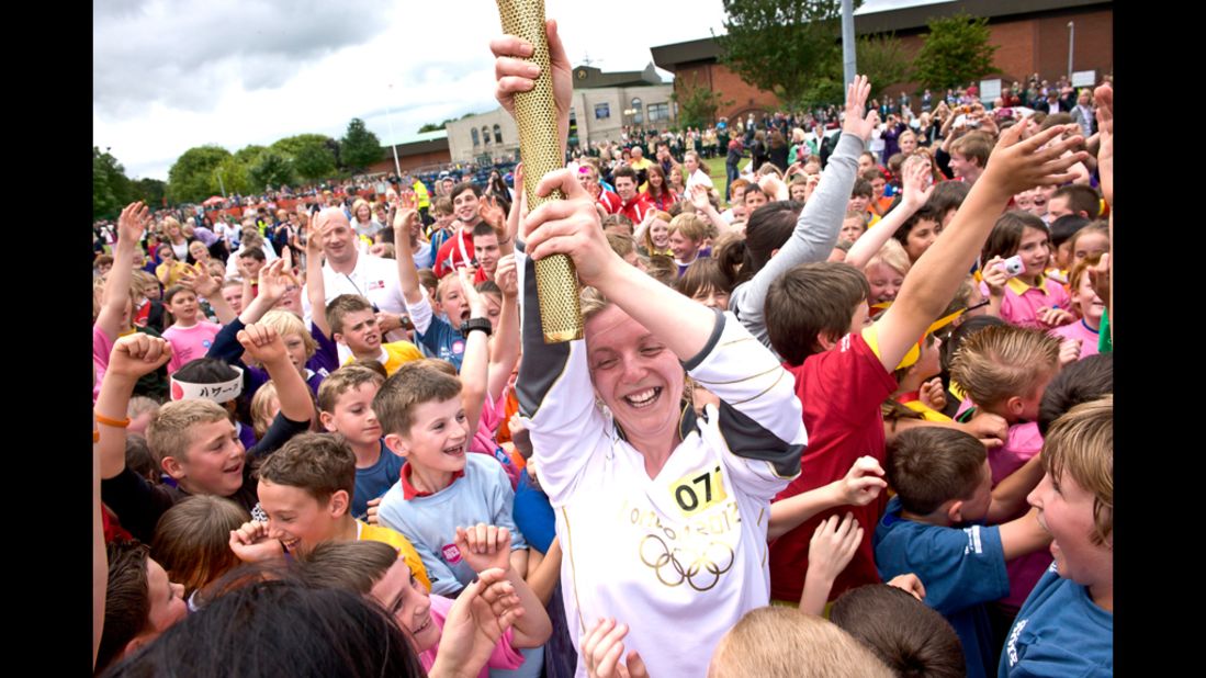 Lauren Reeder, a teaching assistant, is surrounded by local children while carrying the torch in King's Lynn, England, on July 4.