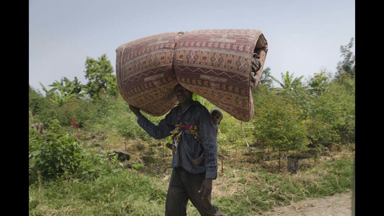 A refugee carries a baby and a bed roll to the Kiwanja refugees camp.