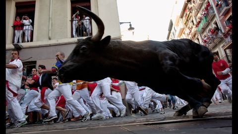 Revelers run beside a Don Juan Pedro Domecq fighting bull on Friday at Curva Estafeta.
