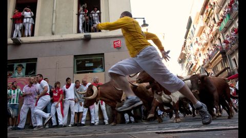 Revelers run beside Don Juan Pedro Domecq fighting bulls at Curva Estafeta on Friday.