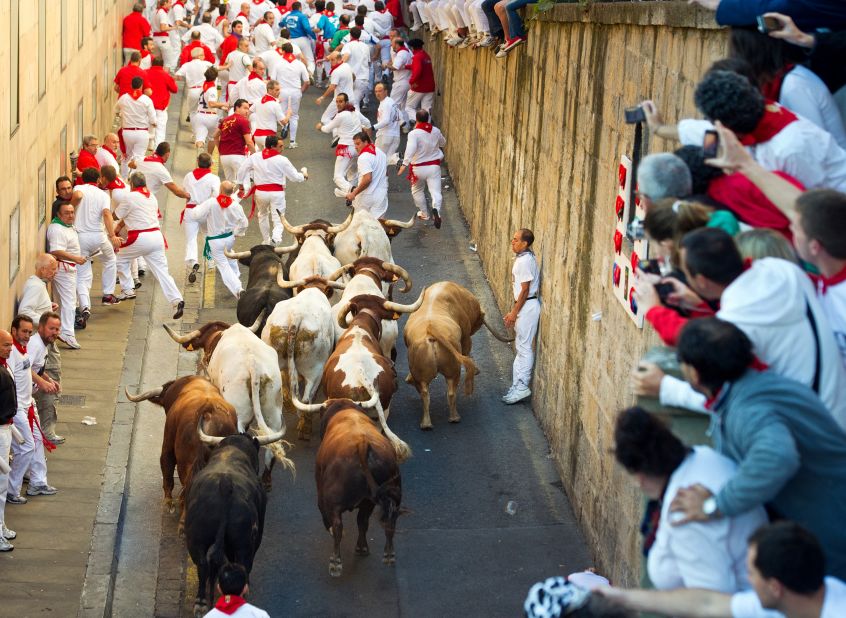 People take pictures as participants run by during the Running of the Bulls in Pamplona, Spain, on Friday, July 13.