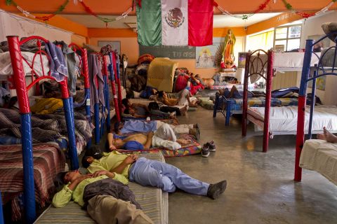 Some nap, while others watch television, at the Casa del Migrante. Residents of the neighborhood have called for the immigrant shelter to close.