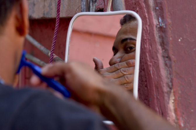 An immigrant shaves outside the shelter, taking a break after days as a stowaway on a cargo train heading north.