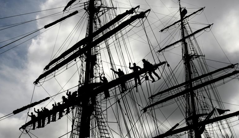 Relay fans watch Andrew Clutton from the top of a ship's mast as he carries the Olympic flame between Hamworthy and Poole on Friday, July 13.