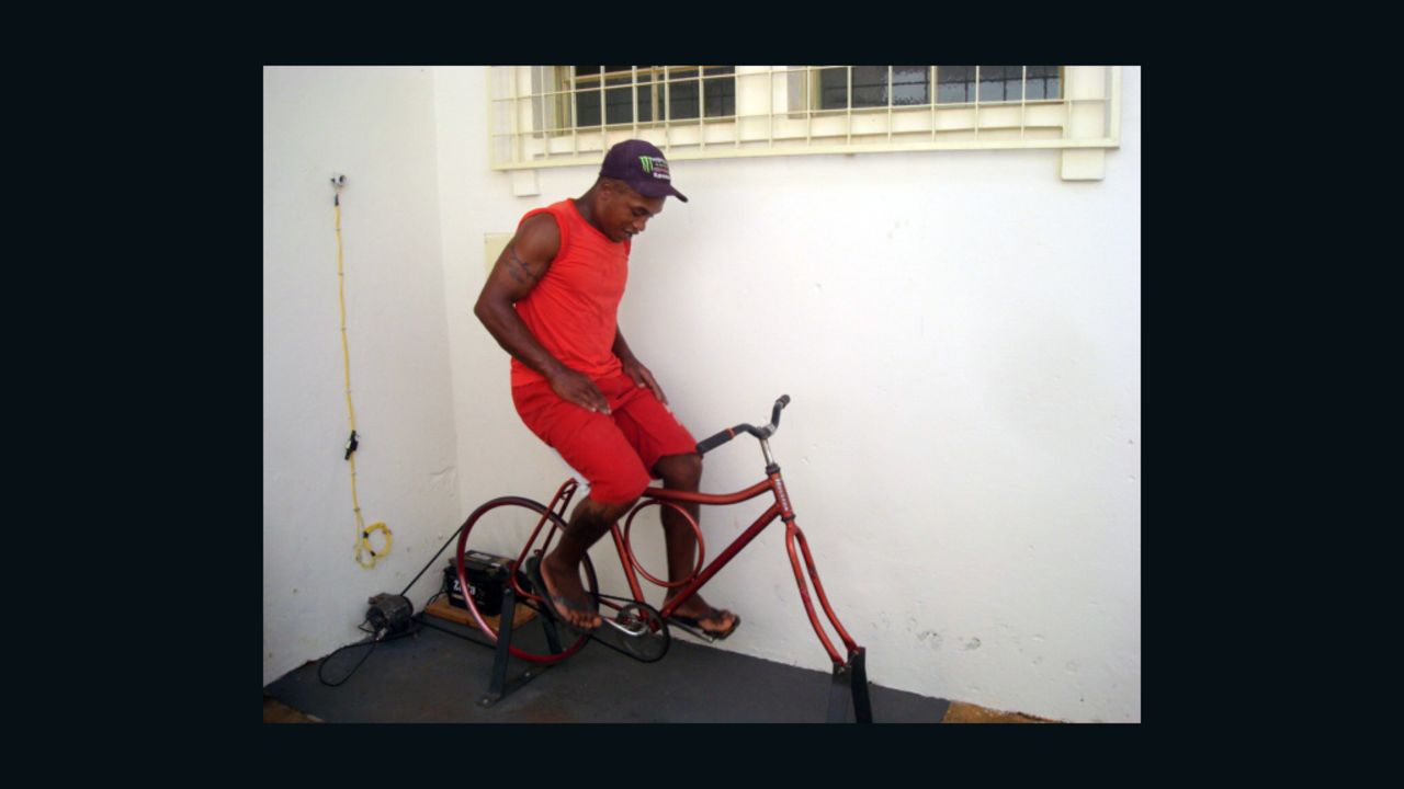 A Brazilian inmate charges a battery while pedaling a stationary bicycle.
