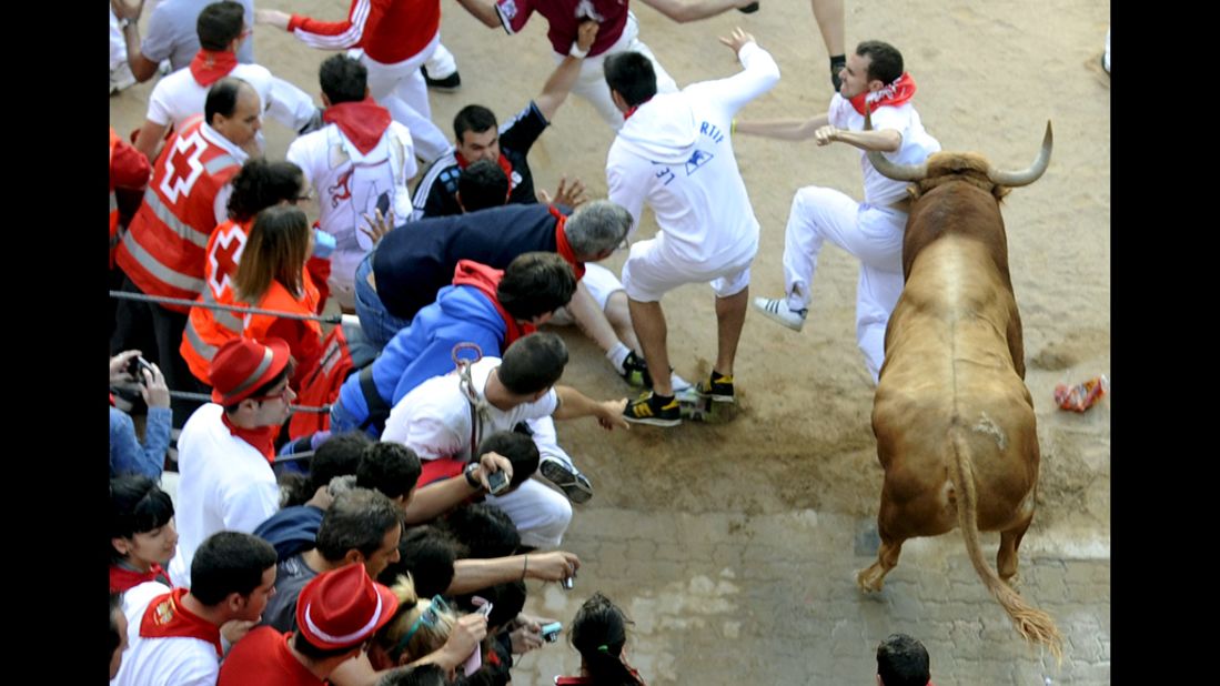 Spectators watch as a participant is hit by a bull Saturday.