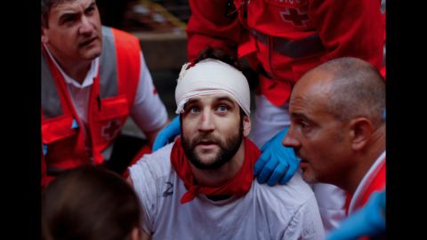 A wounded man is treated for a head injury after running with Torrehandilla Torreherberos fighting bulls on Saturday.