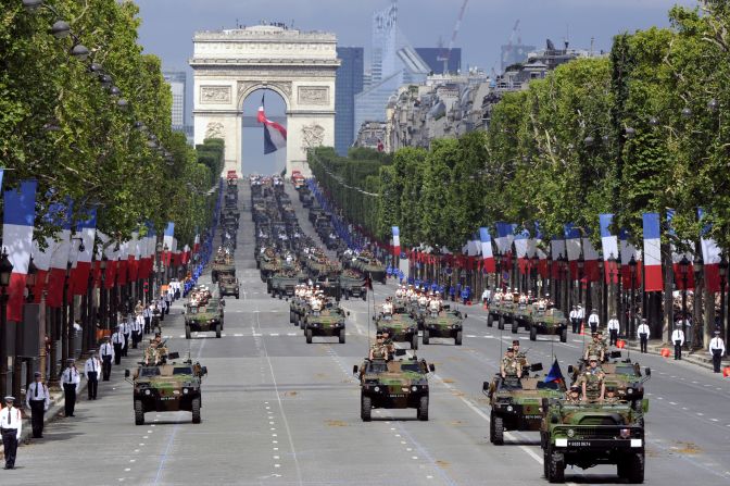 Soldiers from the 92nd Infantry Regiment march down the Champs Elysees with Panhard light armoured vehicles.