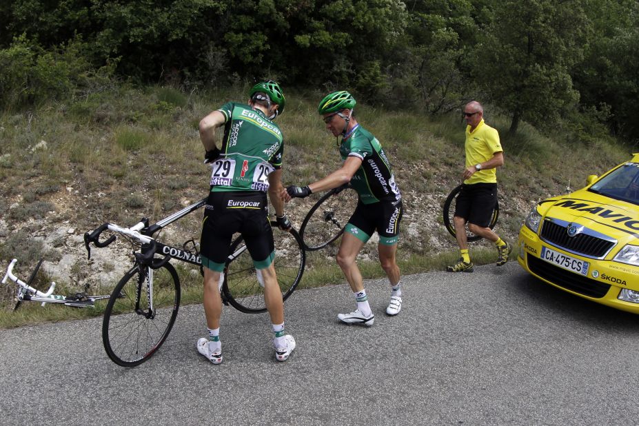 France's Thomas Voeckler, center, helps teammate Pierre Rolland of France, left, change a wheel during the race Sunday. Around 30 punctured tires were reported near the top of the last major climb, apparently caused by tacks thrown on the course by spectators.