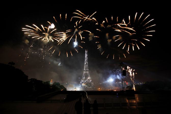 People watch as fireworks illuminate the night sky near the Eiffel Tower during the annual Bastille Day celebrations on July 14, 2012 in Paris. 