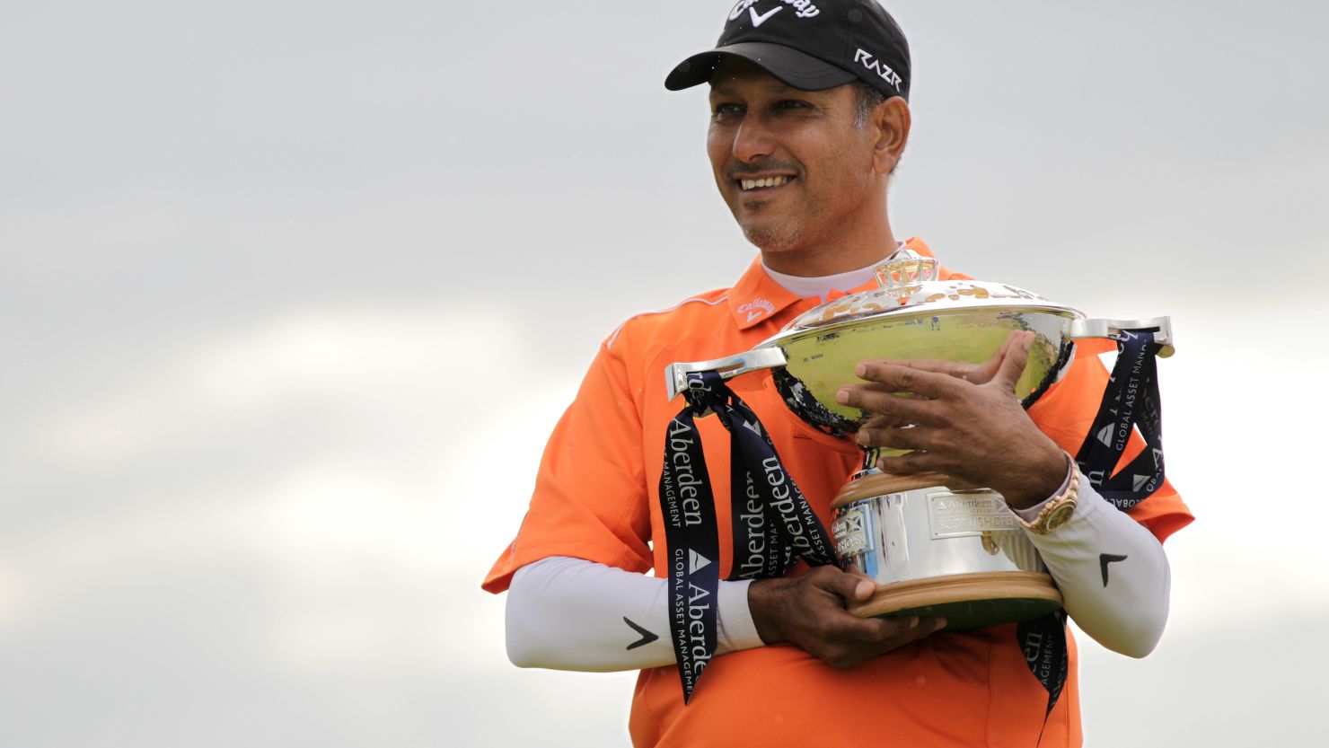 Jeev Milkha Singh cradles the Scottish Open trophy after beating Italy's Francesco Molinari in a playoff on Sunday