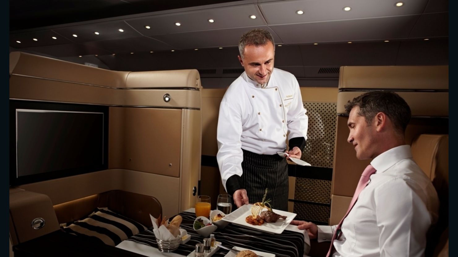An Etihad Airways chef serves up an in-flight meal to a passenger in the first-class cabin.