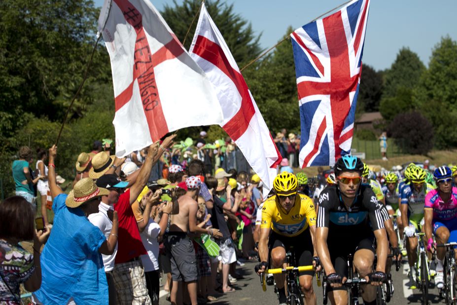 Fans applaud Great Britain's Bradley Wiggins, here in the yellow jersey, as he makes his way up a climb in the main group Monday.