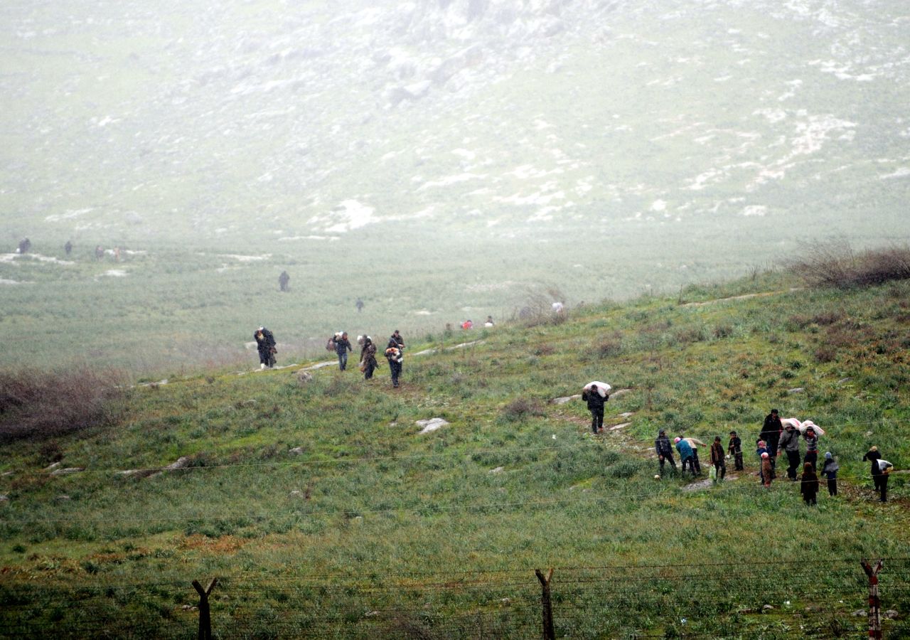 Syrian refugees walk across a field before crossing into Turkey on March 14.