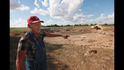 Farmer Marion Kujawa looks over a dried-up pond where his cattle used to water, near Ashley, Illinois, on July 16.  Kujawa is digging the pond deeper so that the water will last longer in the future.