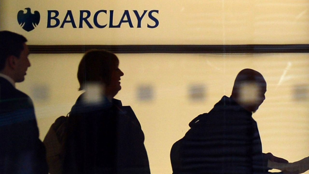People walk past a Barclays logo at the bank's headquarters in Canary Wharf in east London, on July 3, 2012. 