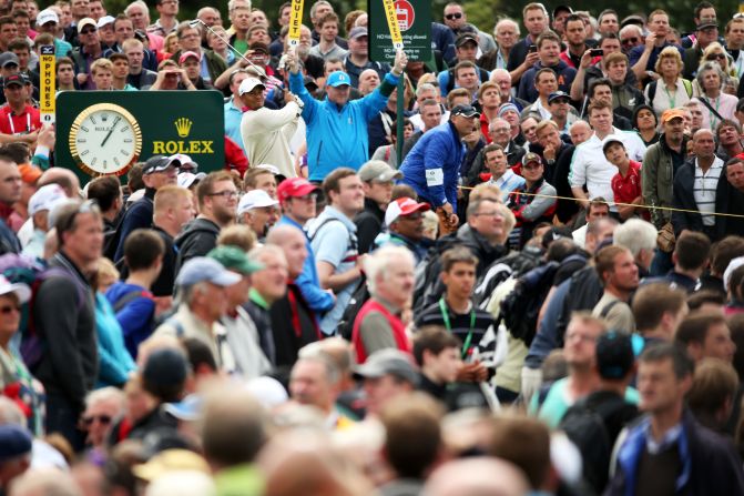 Amid a sea of spectators, Woods plays a shot to the green on the 14th hole Thursday.