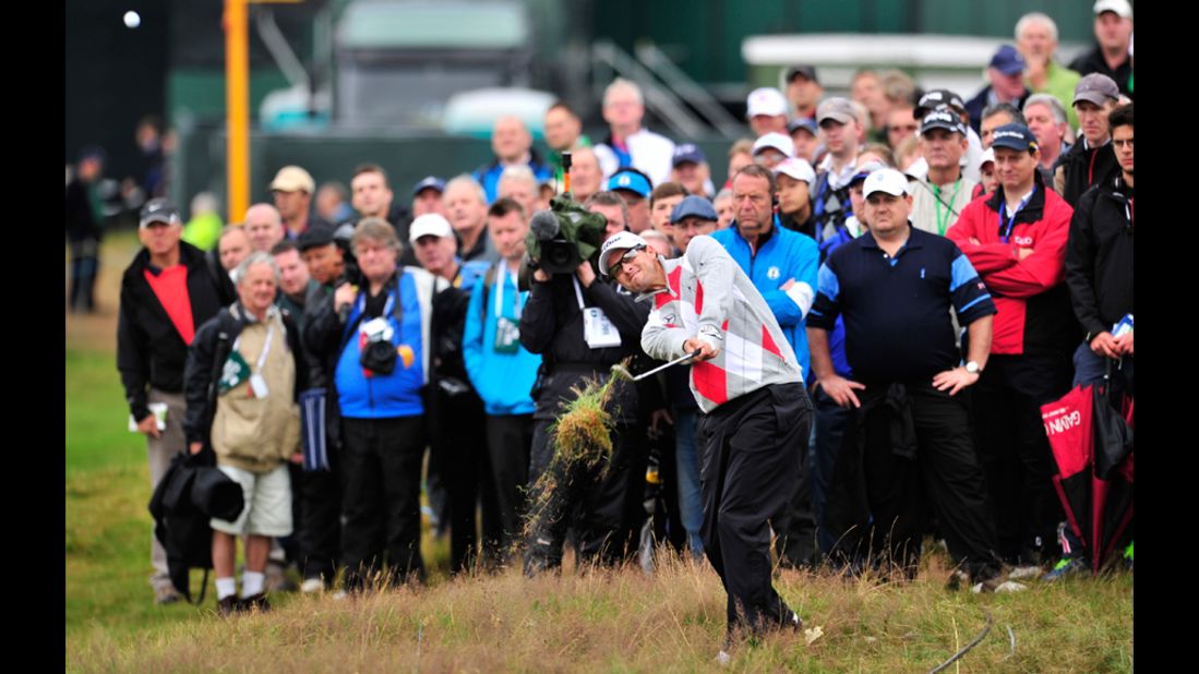 Adam Scott of Australia plays out of the rough on the second hole Thursday under the watchful eyes of spectators.
