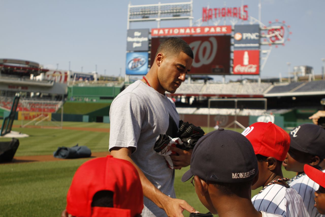Here, Washington Nationals shortstop Ian Desmond passes out batting gloves to the team at Nationals Park.  It is one of several Major League Baseball parks the inner city Little League team is visiting this summer as a tribute to Jackie Robinson and the Negro Leagues. 
