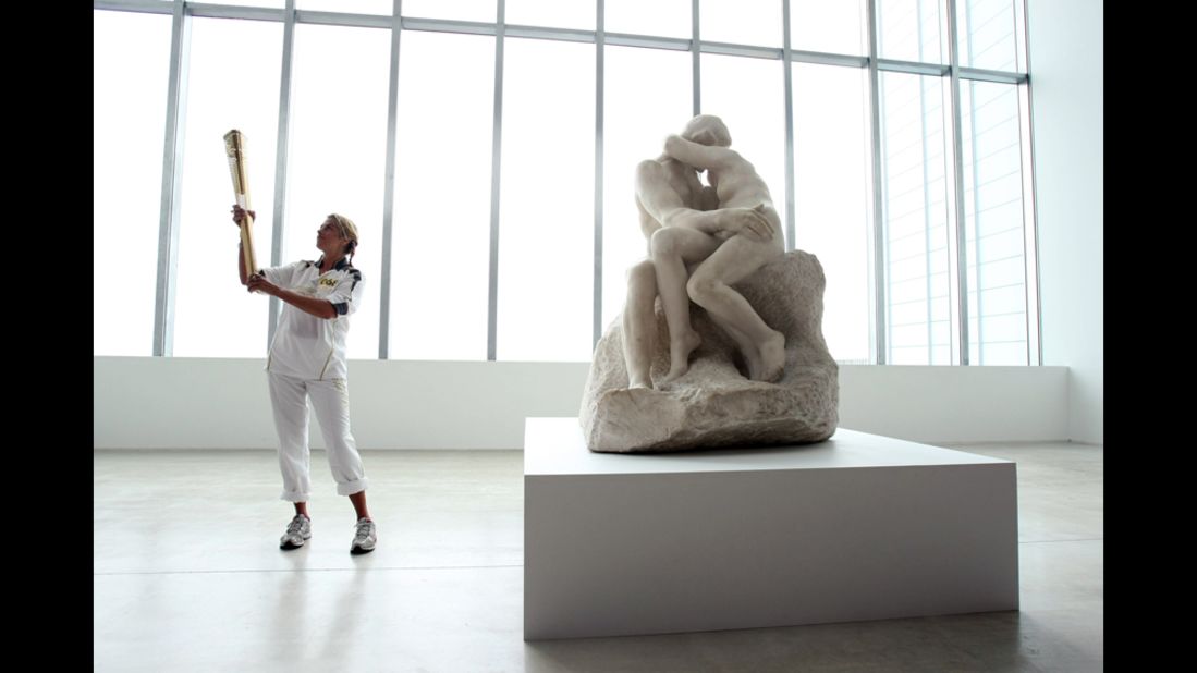 British artist Tracey Emin holds the Olympic flame inside the Turner Contemporary Gallery in Margate alongside "The Kiss" sculpture by Rodin on Thursday, July 19. 
