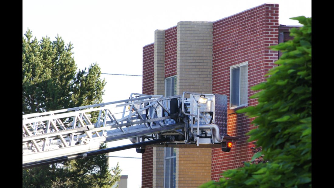 Authorities gather at the shooting suspect's apartment building in Aurora. Police broke a second-floor window to look for explosives the suspect claimed were in the apartment. 