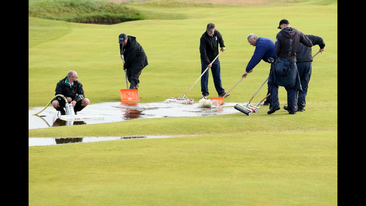 Members of the grounds crew clear water on the course Friday during the second round.