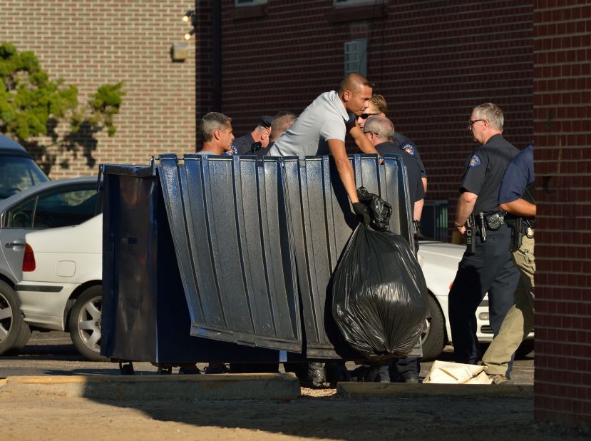Agents search the trash container outside the suspect's apartment in Aurora.