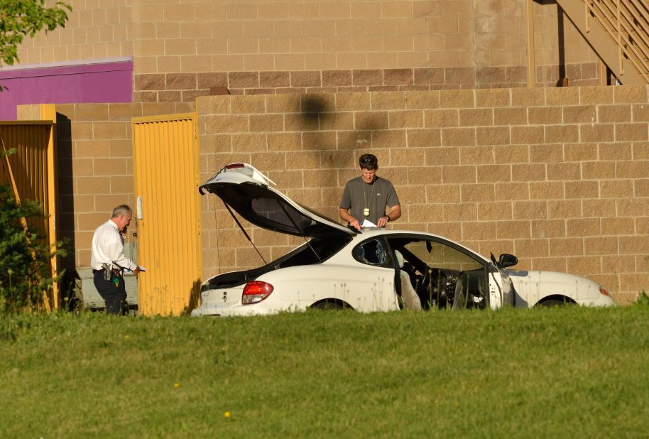 Agents search the suspect's car outside the theater.