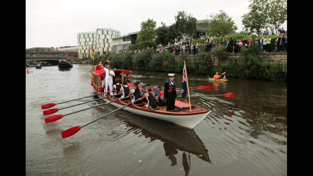 David Boyle carries the flame on a boat rowed by the Maidstone Rowing Club during his leg through Maidstone, England, on July 20.