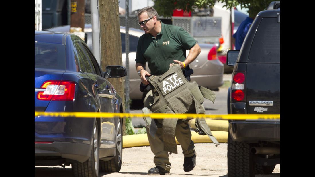 A Federal ATF officer carries protective gear onsite at the home of the shooting suspect.