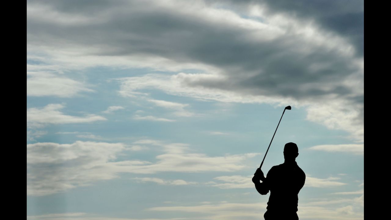 Woods takes practice swings at No. 15 under gray wisps of clouds during Friday's round.