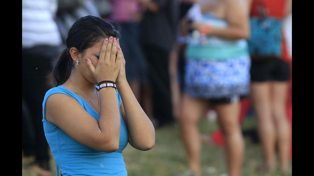 A woman grieves during a vigil for victims behind the theater.