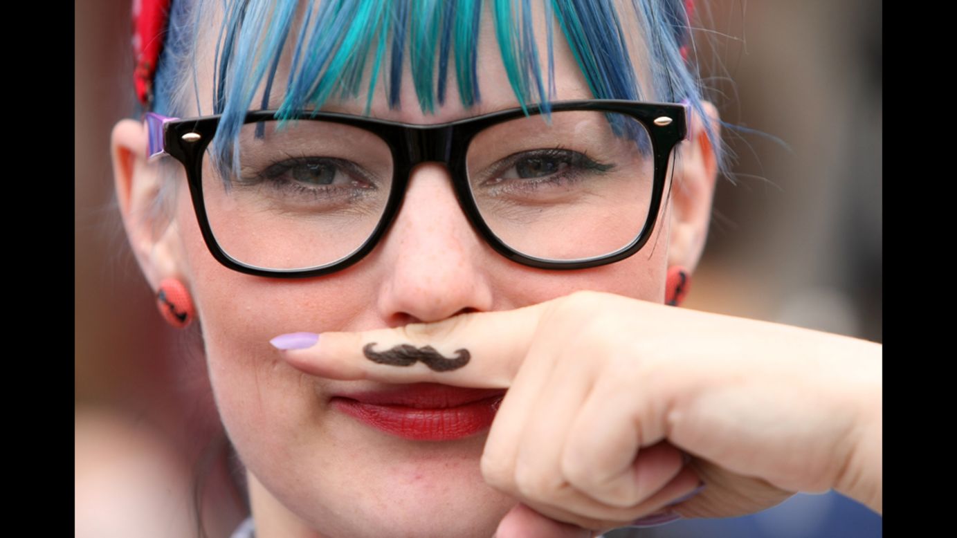 A woman attending the Hipster Olympics 2012 holds her finger to her face, displaying a drawn-on "ironic mustache" Saturday, July 21.