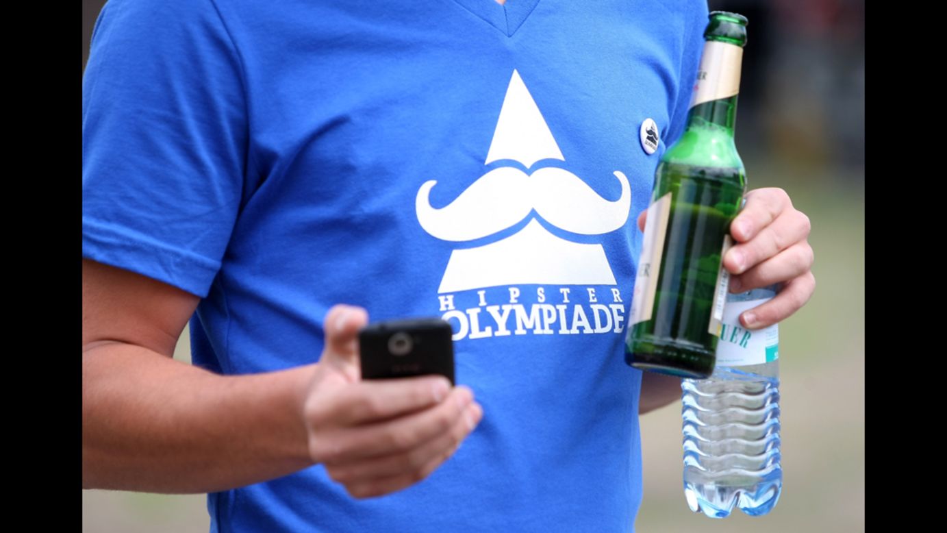 An attendant wearing a "Hipster Olympiade" T-shirt checks his phone.