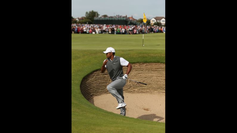 Woods scrambles out of a greenside bunker after hitting the ball close on fifth hole.